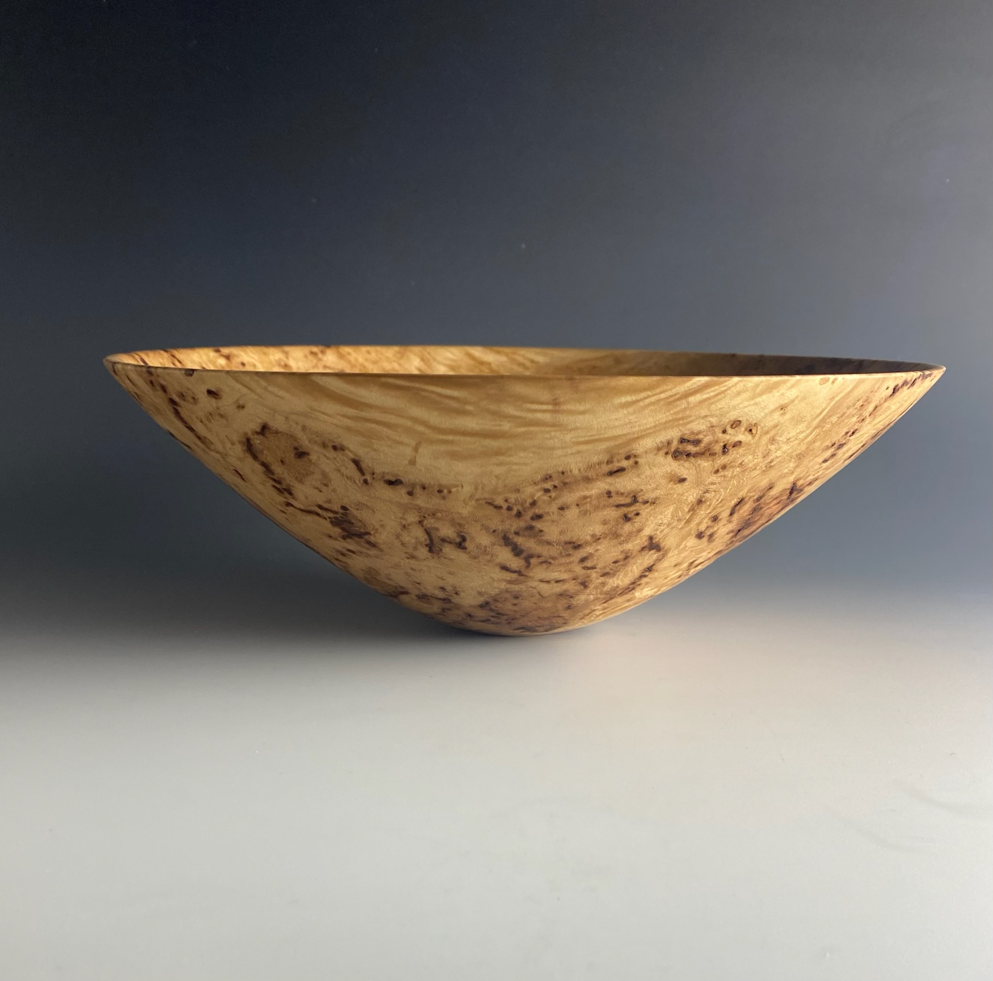 Wide shallow bowl in golden spalted burl, thin walls and elegant tapered form.