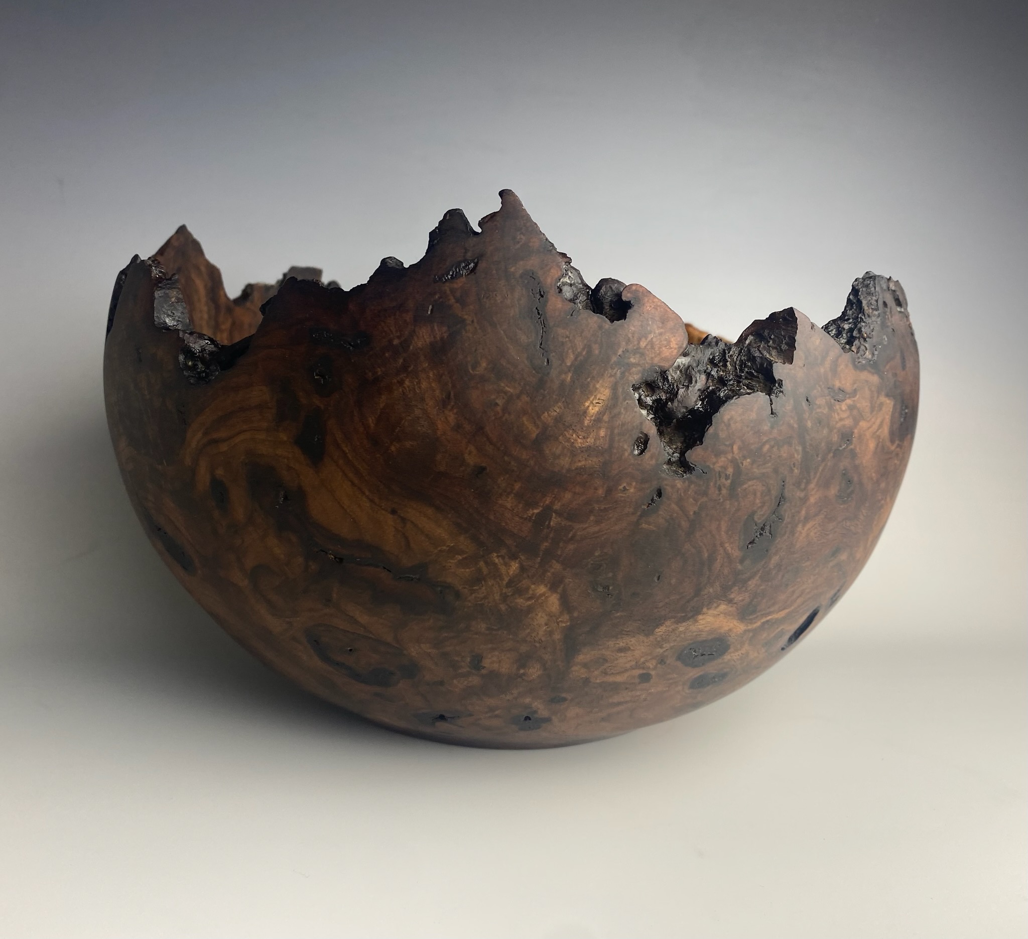 Dark burl bowl with dramatic natural live-edge rim.