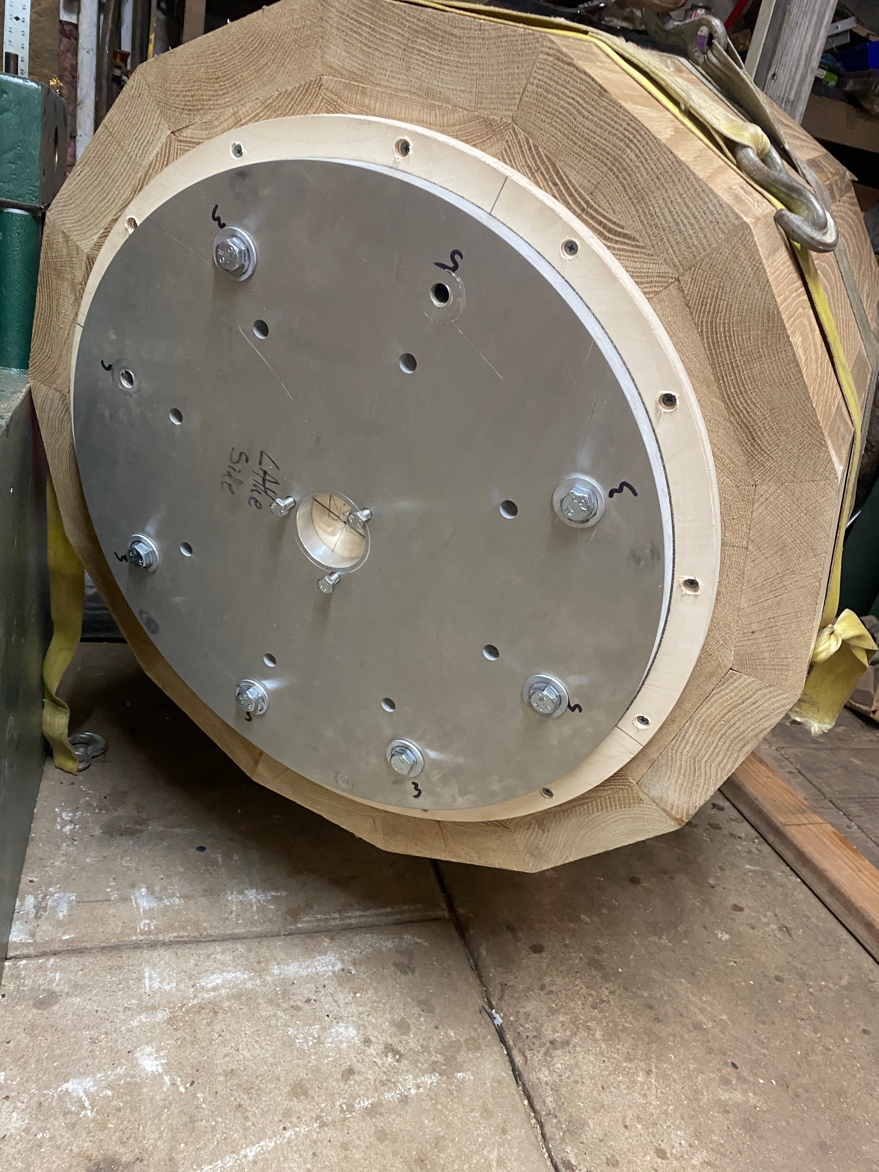 End face of the blank showing the large steel faceplate bolted on, yellow strap wrapped around the blank.